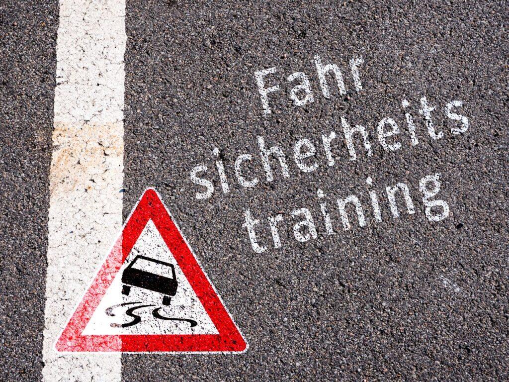 Straßenmarkierung mit der Aufschrift „Fahrsicherheitstraining“ und Schleudergefahr-Symbol – wichtig für jeden Schleuderkurs.