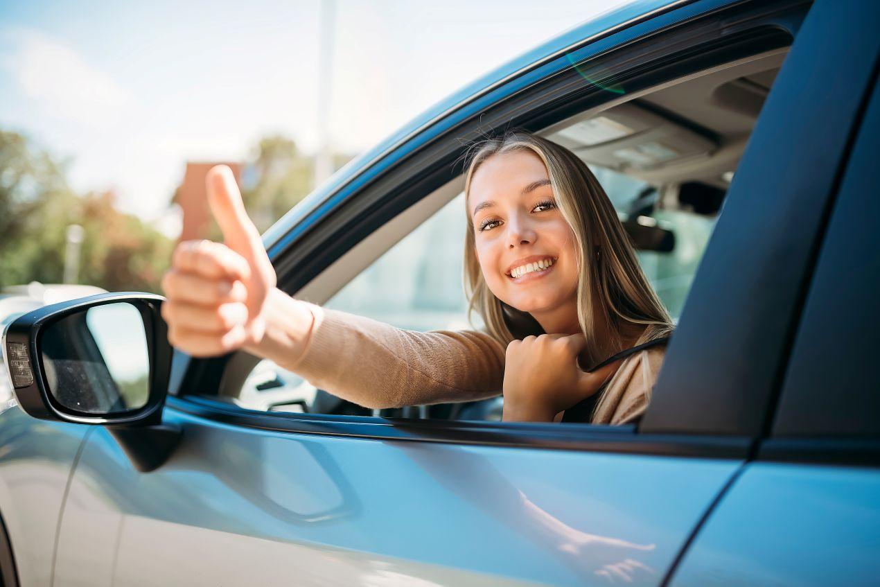 Junge Frau im Auto zeigt Daumen hoch – Fahrsicherheitstraining und Schleuderkurs für selbstbewusstes Fahren.